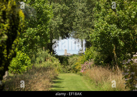 Chiesa Happisburgh visto attraverso un interstizio tra gli alberi a East Ruston Old Vicarage Gardens, Norfolk Foto Stock