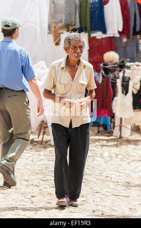 Gizmo cercando locale uomo cubano di fumare una sigaretta a lavorare come un caricatore di denaro in una strada in un mercato in Trinidad, Cuba Foto Stock