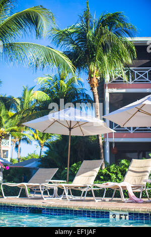 Sedie a sdraio e ombrelloni vicino alla piscina in un hotel di lusso Foto Stock