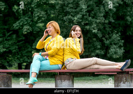 Madre di parlare con sua figlia sul banco di lavoro nel parco Foto Stock