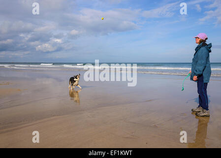 Donna e Border Collie cane giocare a palla sulla spiaggia Bamburgh, Northumberland, Inghilterra Foto Stock