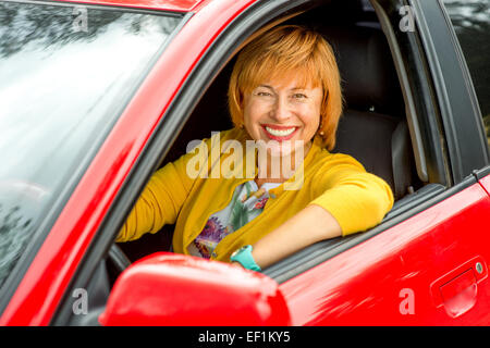 Certi vecchi woman in red car guida Foto Stock