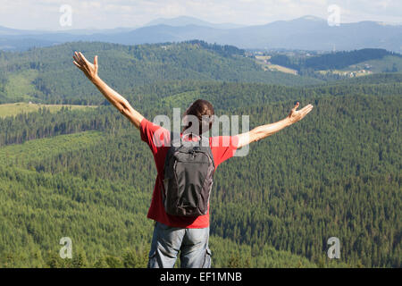 Uomo felice con le mani in alto sulla montagna Foto Stock