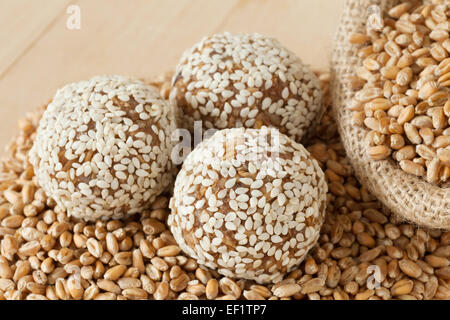 Le sfere di dolce da terra i germogli di frumento con semi di sesamo, grani in sacco di legno sul tavolo da cucina Foto Stock