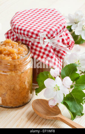 La marmellata di mele e purea in vasetti e cucchiaio di legno sul tavolo da cucina Foto Stock