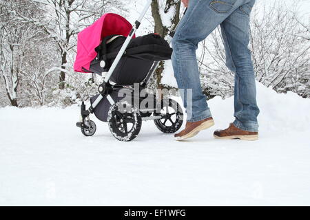 Un padre con il suo bambino in un buggy su una pista innevata Foto Stock