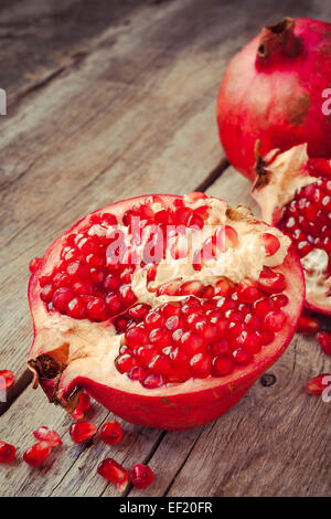 Pezzi di ripe melograno su legno tavolo rustico Foto Stock