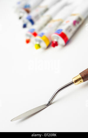 Coltello tavolozza closeup olio e tubi di vernice su bianco artist canvas Foto Stock
