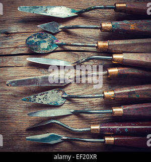 Fila di palette artista coltelli su legno vecchio tavolo rustico, retro stilizzata Foto Stock