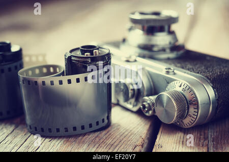 Una vecchia foto rotoli di pellicola, la cassetta e il retro della fotocamera, il fuoco selettivo. Vintage stilizzato. Foto Stock