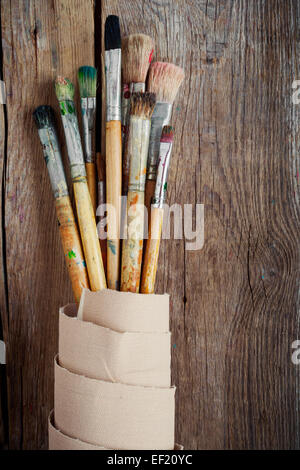 Artista pennelli e rotolo di tela su sfondo di legno Foto Stock