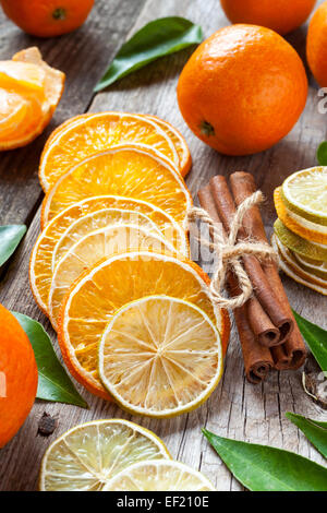 Essiccato fette di arancia e limone, bastoncini di cannella e mature, tangerini sul vecchio tavolo in legno. Foto Stock
