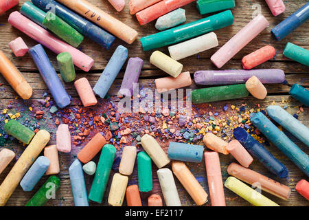 Raccolta di arcobaleno pastello colorato pastelli con polvere di pigmento sulla vecchia scrivania. Foto Stock