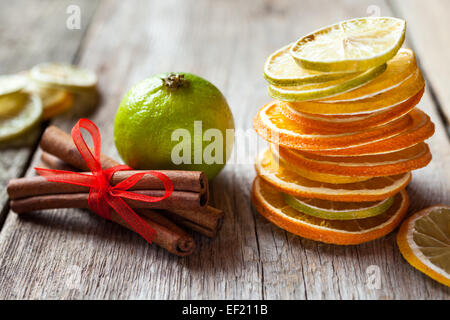 Pila di essiccato fette di arancia e limone, lime e bastoncini di cannella sul vecchio tavolo in legno. Foto Stock