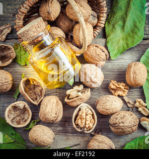 Le noci, la bottiglia di olio di noci e cestello sul vecchio tavolo da cucina. Vista dall'alto. Foto Stock