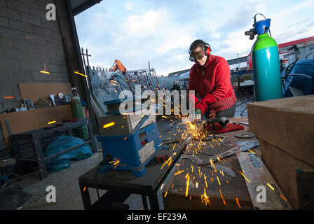 Un saldatore femmina usando una smerigliatrice angolare Foto Stock