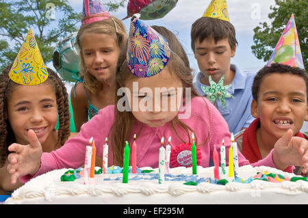 Ragazza soffiando le candeline sulla torta di compleanno Foto Stock