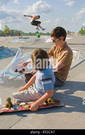 Un giovane uomo e ragazzo seduto a un skatepark con il loro skateboard Foto Stock