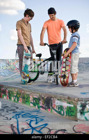 Due giovani uomini e un ragazzo in uno skatepark Foto Stock