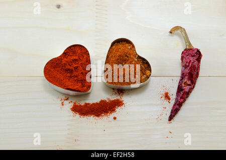 Due cuori di pepe e paprika essiccate su una tavola di legno Foto Stock