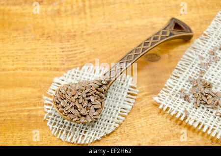 Inciso il cucchiaio di legno riempita con i semi di lino su una tovaglia vintage Foto Stock