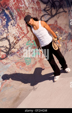 Guidatore di skateboard appendere intorno a skate park Foto Stock