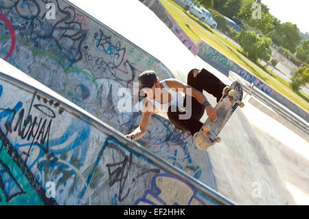 Guidatore di skateboard facendo antenne a un skate park Foto Stock