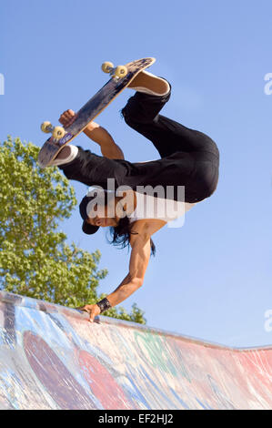 Guidatore di skateboard facendo antenne a un skate park Foto Stock