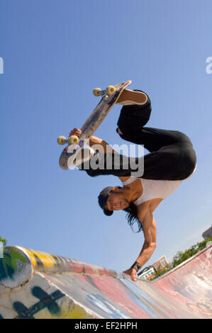 Guidatore di skateboard facendo antenne a un skate park Foto Stock