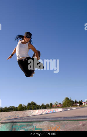 Guidatore di skateboard facendo antenne a un skate park Foto Stock