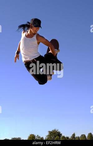 Guidatore di skateboard facendo antenne a un skate park Foto Stock