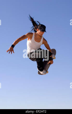 Guidatore di skateboard facendo antenne a un skate park Foto Stock