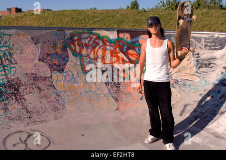 Guidatore di skateboard appendere intorno a skate park Foto Stock