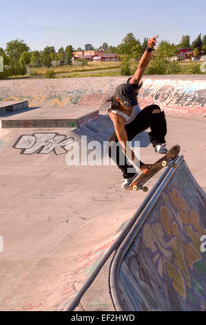 Guidatore di skateboard facendo una antenna a skate park Foto Stock