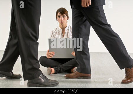 Donna seduta sul pavimento dietro due uomini Foto Stock