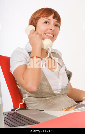 Dai capelli rossi donna parlando al telefono alla sua scrivania Foto Stock