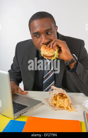 Imprenditore di mangiare il pranzo alla sua scrivania Foto Stock