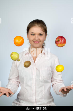 Giovane donna indossa camicia e gioca con frutti Foto Stock