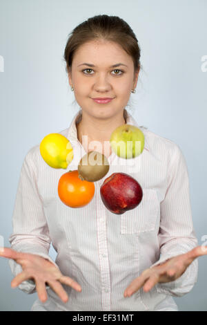 Giovane donna indossa camicia e gioca con frutti Foto Stock