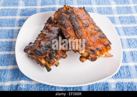 Barbecue costolette su un posto bianco con salsa piccante Foto Stock