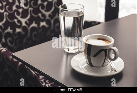 Tazza di caffè e un bicchiere di acqua sulla tavola in una caffetteria. Foto Stock