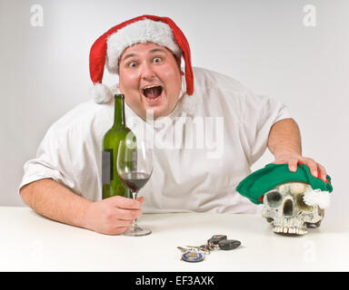 Il sovrappeso uomo beve vino indossando un cappello da Babbo Natale Foto Stock