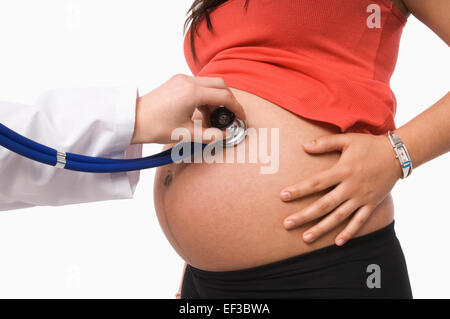 Il medico ascolta con uno stetoscopio la pancia di una donna incinta,  sfondo blu Foto stock - Alamy