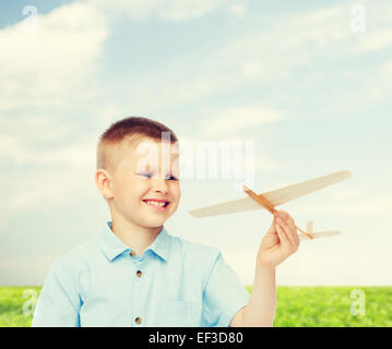 Sorridente ragazzino tenendo un legno modello di aeroplano Foto Stock