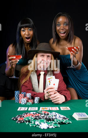 Due donna in piedi dietro un uomo giocando a poker Foto Stock