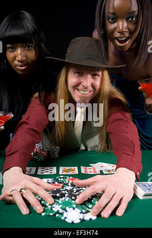 Due donna in piedi dietro un uomo giocando a poker Foto Stock