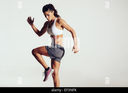 Montare attraente donna esercita in studio con copyspace. Immagine di sano giovane atleta femminile facendo allenamento fitness contro gr Foto Stock