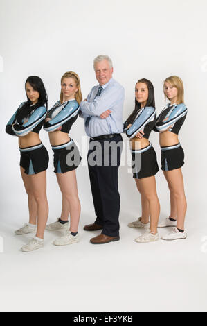 Cheerleader in piedi con docente Foto Stock