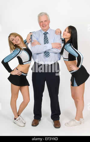 Cheerleader in piedi con docente Foto Stock