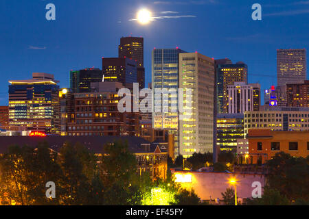 La luna piena che si eleva al di sopra del Denver, Colorado skyline notturno Foto Stock